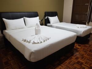 two beds in a hotel room with white sheets at Sandra Homestay in Tawau
