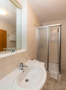ein Badezimmer mit einem weißen Waschbecken und einer Dusche in der Unterkunft Klostergasthof Maria Eck in Siegsdorf
