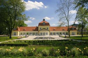 a large yellow building with a red roof at Thermalis - Das Boardinghouse im Kurpark Bad Hersfeld in Bad Hersfeld