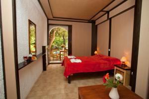 a bedroom with a red bed with a red blanket at Damnoni Paradise in Damnoni