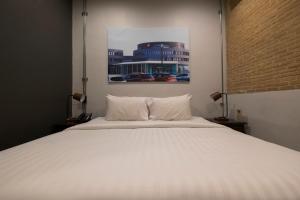 Un dormitorio con una cama blanca y un cuadro en la pared. en Iron32 Hotel, en Chiang Mai