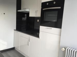 cocina con armarios blancos y microondas negro en T2 hyper centre bord de Loire Parking en Nantes