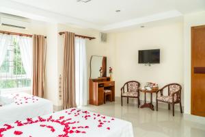 a bedroom with two beds and a table and a television at Sun & Sea Hotel in Phu Quoc