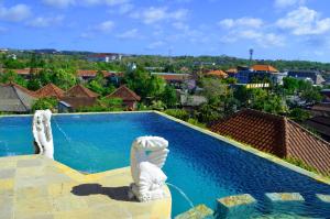 a swimming pool with two white statues next to it at Nirmala Hotel Jimbaran in Jimbaran