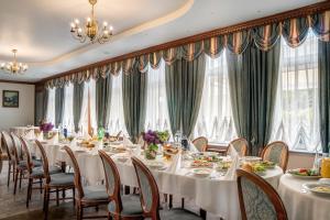 a dining room with tables and chairs and windows at Hotel Karczówka in Kielce