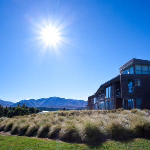 a building on a hill with the sun in the sky at Peppers Bluewater Resort in Lake Tekapo