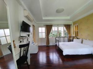 Schlafzimmer mit einem großen weißen Bett und Holzböden in der Unterkunft Baan Kung Kang De Pai in Pai
