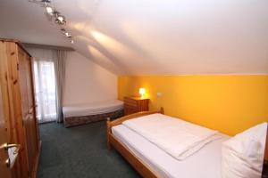 sypialnia z 2 łóżkami i żółtą ścianą w obiekcie Pension Reiterhaus w mieście Wagrain