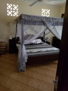 a bed with a canopy in a room at Villa LeoMar Diani Beach in Diani Beach