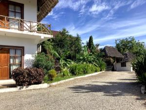 a driveway leading to a house with a balcony at Shamba Lodge in Nungwi