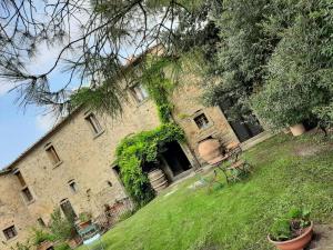 Agriturismo Frantoio Valiani في كورتونا: مبنى من الطوب القديم مع اللبي ينمو عليه