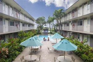 a courtyard with tables and umbrellas and a swimming pool at Pacific Marina Inn in Honolulu
