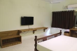 Habitación con 2 camas y TV en la pared. en Indian Residency, en Tiruchchirāppalli
