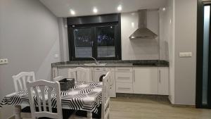 cocina con mesa, sillas y fregadero en Carballos Altos-Apartamentos Turísticos, en Arzúa