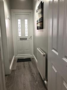 a hallway with a white door and a window at Beechwood Garden Suite in Newtownabbey