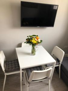 a white table with a vase of flowers on it at Beechwood Garden Suite in Newtownabbey