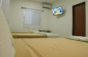 a hospital room with two beds and a television at Pousada Parapuã in Caraguatatuba