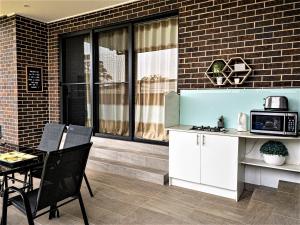 a kitchen with a table and a microwave on a brick wall at Revesby New Self Contained Granny Flat in Revesby