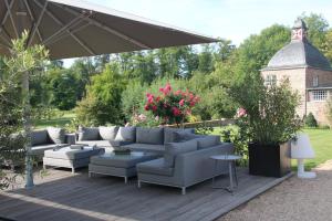 een patio met een bank, stoelen en een parasol bij Apartment 1 in Korschenbroich