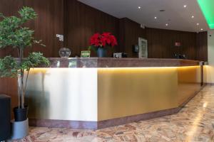 eine Lobby mit einer goldenen und weißen Theke mit Topfpflanzen in der Unterkunft H&L Hotel in Cinisello Balsamo