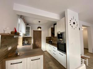a kitchen with white cabinets and a clock on the wall at Villa Jarka Rent in Ždiar