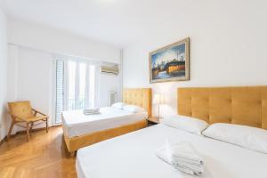 una habitación de hotel con 2 camas y una silla en Victoria Plaza Palace Apartments, en Atenas