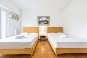 Habitación con 2 camas, paredes blancas y suelo de madera. en Victoria Plaza Palace Apartments, en Atenas