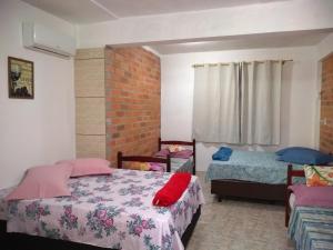 um quarto com 2 camas e uma parede de tijolos em Canto da Praia em Itajubá