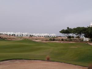 uma vista para um campo de golfe com edifícios ao fundo em Las Terrazas Golf Resort Rental em Roldán