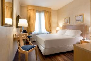 a hotel room with a white bed and a chair at Hotel De Londres in Rimini