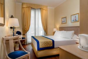 a hotel room with a bed and a desk at Hotel De Londres in Rimini