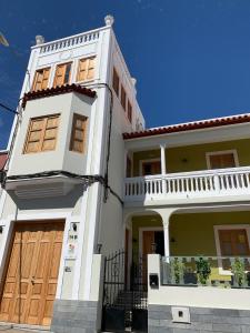 duży biały dom z drewnianymi drzwiami w obiekcie Albergue Gran Canaria w mieście Las Palmas de Gran Canaria