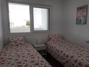 a bedroom with two beds and two windows at Las Terrazas Golf Resort Rental in Roldán