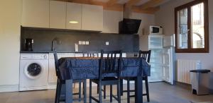 une cuisine avec une table et des chaises ainsi qu'un lave-linge dans l'établissement Grange de caractère en pierre al badiu, à La Llagonne