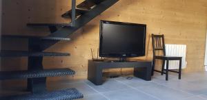 une télévision assise sur un bureau à côté d'un mur en bois dans l'établissement Grange de caractère en pierre al badiu, à La Llagonne