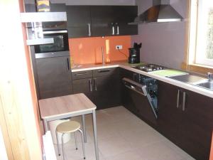 kuchnia z brązowymi szafkami, stołem i zlewem w obiekcie Bungalow w mieście Froid-Chapelle