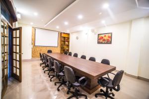 una sala de conferencias con una gran mesa de madera y sillas en Apsara Guest House en Shillong