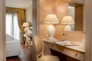 a hotel room with a desk and a mirror at Hotel De Londres in Rimini
