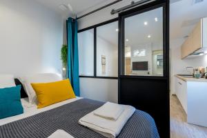 - une chambre avec un lit doté d'oreillers jaunes et bleus dans l'établissement Le Clemenceau, à Antibes