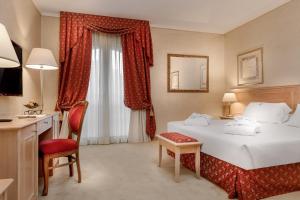 a hotel room with a bed and a desk and a chair at Hotel De Londres in Rimini