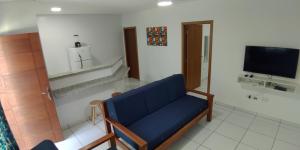 a living room with a blue couch and a tv at Residencial JL Maresias Apartamentos in Maresias