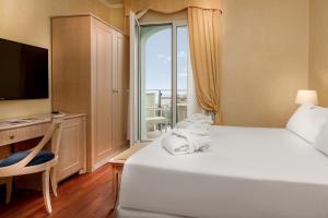 a hotel room with a bed and a large window at Hotel De Londres in Rimini
