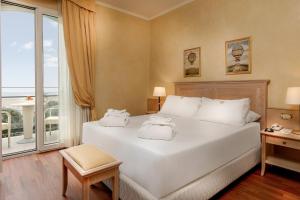 a bedroom with a large white bed and a window at Hotel De Londres in Rimini