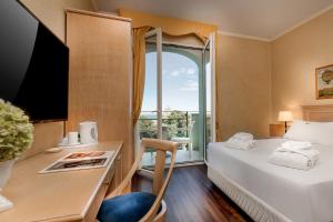 a hotel room with a bed and a desk and a window at Hotel De Londres in Rimini