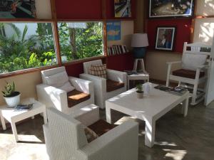 un restaurante con sillas blancas, mesas y ventanas en Beach Hotel Casa Nina en Las Terrenas