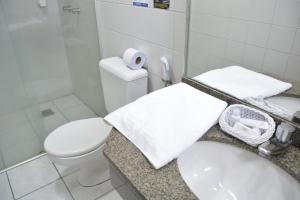 a bathroom with a toilet and a sink with towels at Brumado Hotel in Campo Grande