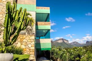 un edificio con una palmera y montañas en el fondo en Pousada Vie en Vale do Capao