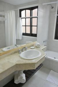 a white bathroom with a sink and a tub at Apart Hotel Las Hadas Carilo in Carilo