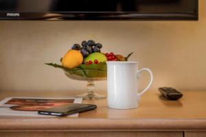 a cup of coffee and a bowl of fruit on a table at Hotel De Londres in Rimini