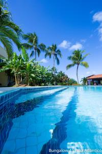 uma piscina com palmeiras ao fundo em Pipa Atlântico Bungalow 41 em Pipa